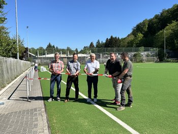 Das Bild zeigt fünf Personen, welche ein Band zur Eröffnung des Jahnstadions durchschneiden.