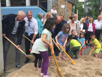 Das Bild zeigt kommunale Vertreter und Kinder beim Spatenstich