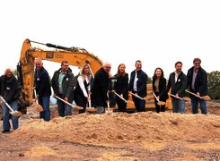 Stadt Maintal Das Bild zeigt Personen, die einen Spatenstich durchführen. Im Hintergrund ist ein Bagger zu sehen.