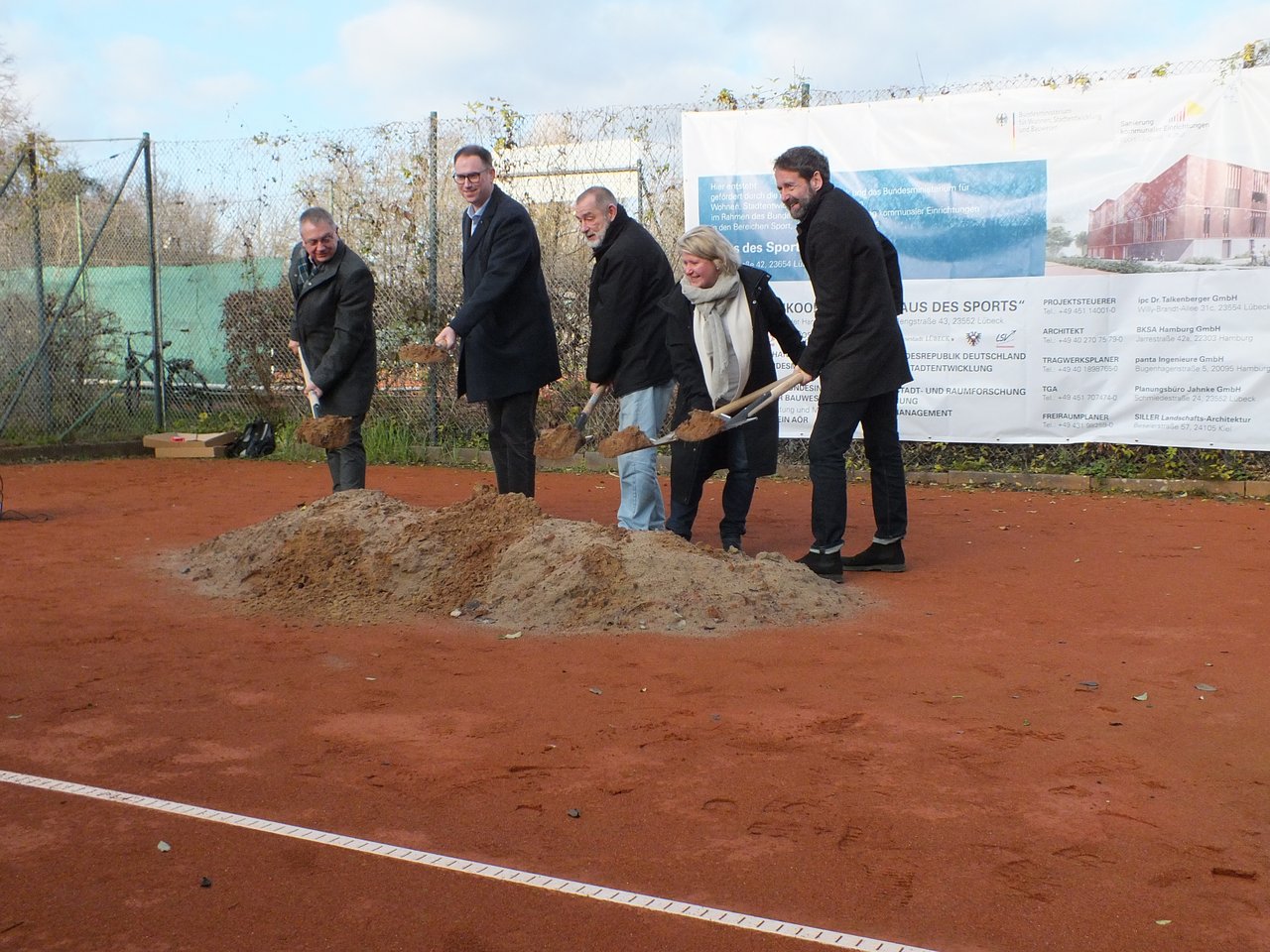 Das Bild zeigt fünf Personen, die einen Spatenstich begehen, indem sie Erde mit einem Spaten aufheben.