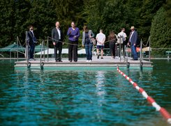 Eine Gruppe Menschen steht am Rand eines Schwimmerbeckens in einem Freibad.